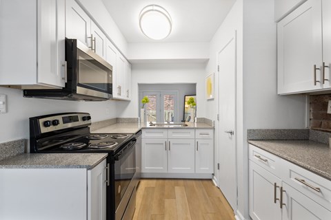 A kitchen with white cabinets and a black stove top oven.