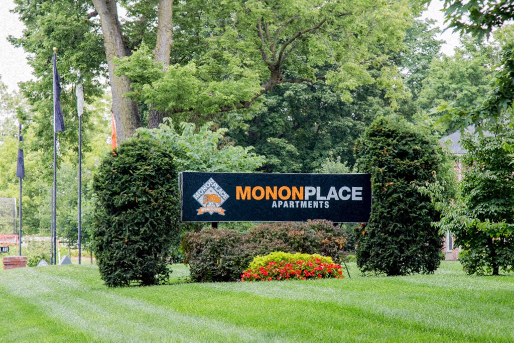 a sign formonopolice apartments in front of some trees and grass