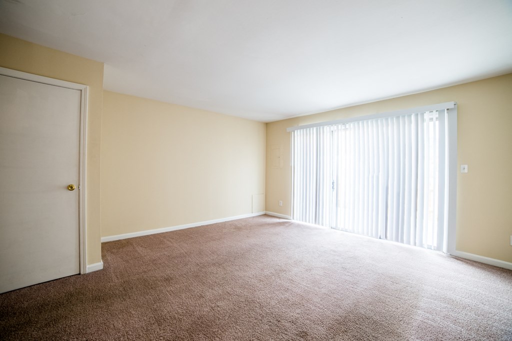 an empty living room with blinds and a window