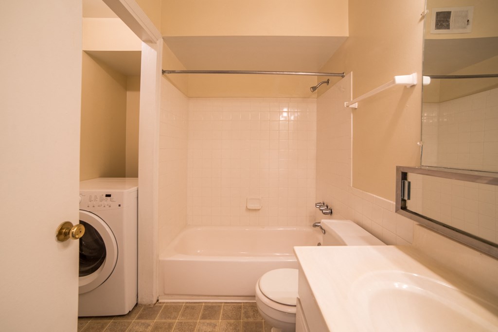 a bathroom with a toilet sink and tub and a washing machine