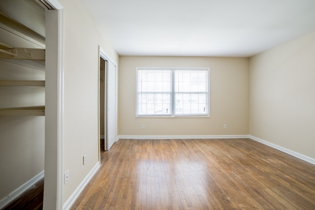 an empty living room with wood floors and a window