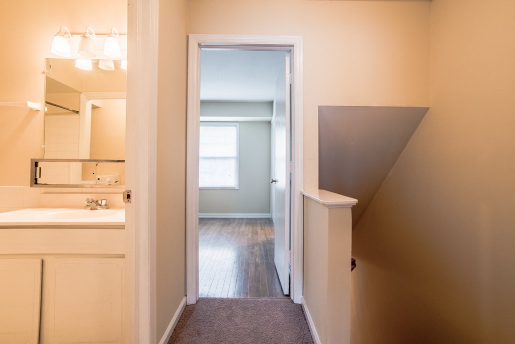 an empty hallway with a sink and a doorway to a bathroom