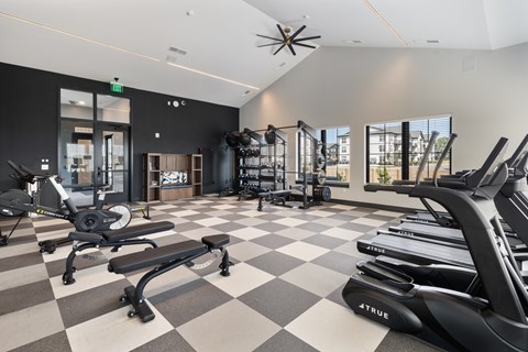 Modern fitness center with treadmills, cardio equipment, free weights, strength-training equipment, and workout benches at Montage West Lafayette apartments in West Lafayette, IN.