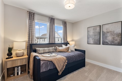 Comfortable apartment bedroom at Mural Lewis Center featuring large windows with natural light, plush bedding, neutral color palette, ceiling light fixture, and modern decor