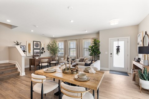 Bright open-concept dining and living space at Mural Lewis Center featuring wood-style flooring, large windows, modern dining table, neutral decor, and seamless flow into the kitchen and living room