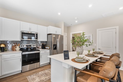 A modern kitchen with a dining table set for two.