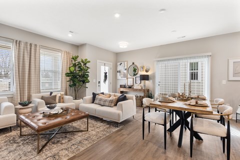 A well-lit living room with a brown leather coffee table and white sofas.