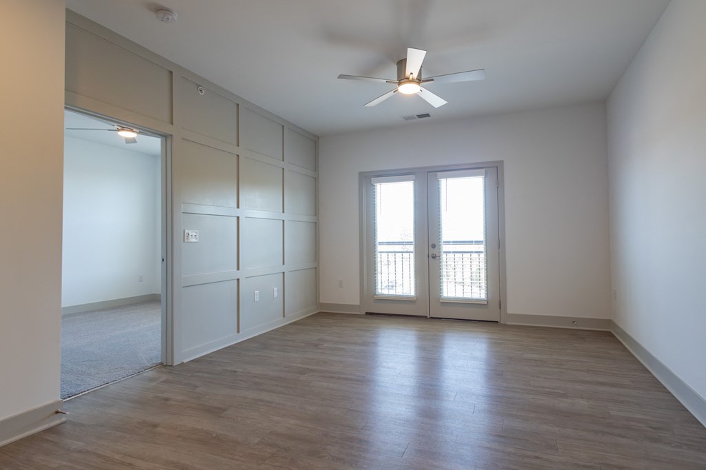 an empty living room with white walls and a ceiling fan