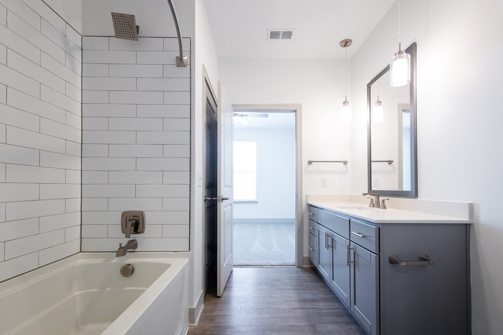 a white bathroom with a tub and a sink and a mirror