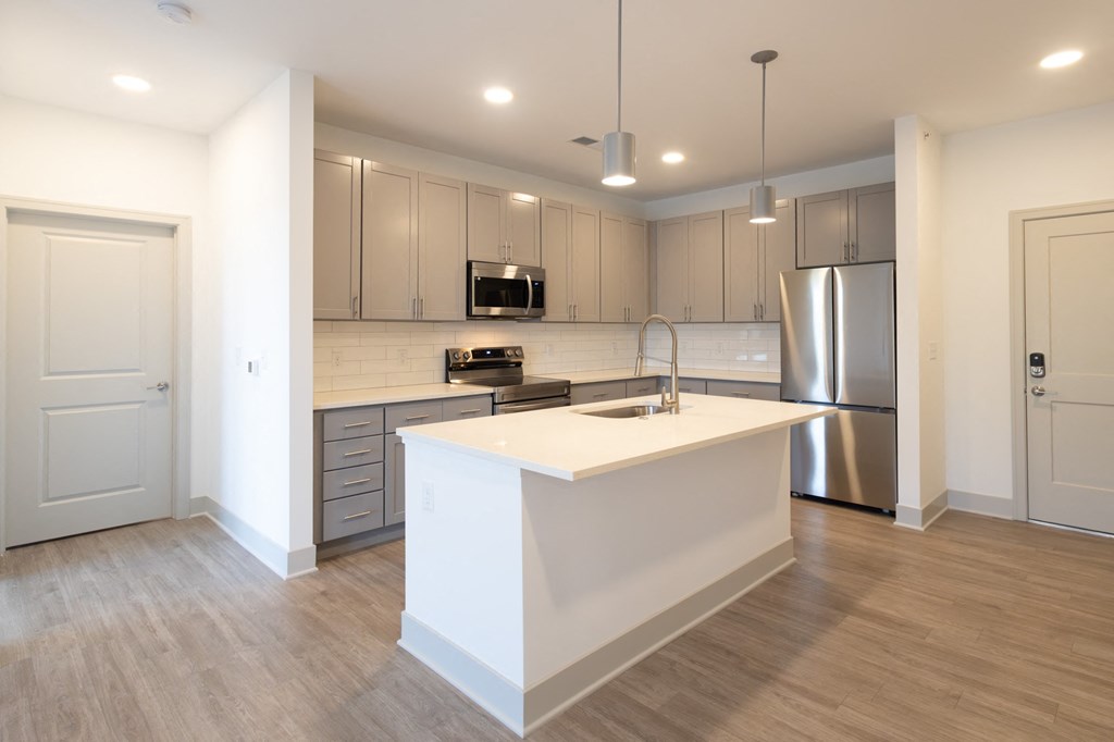 a white kitchen with a large island and stainless steel appliances
