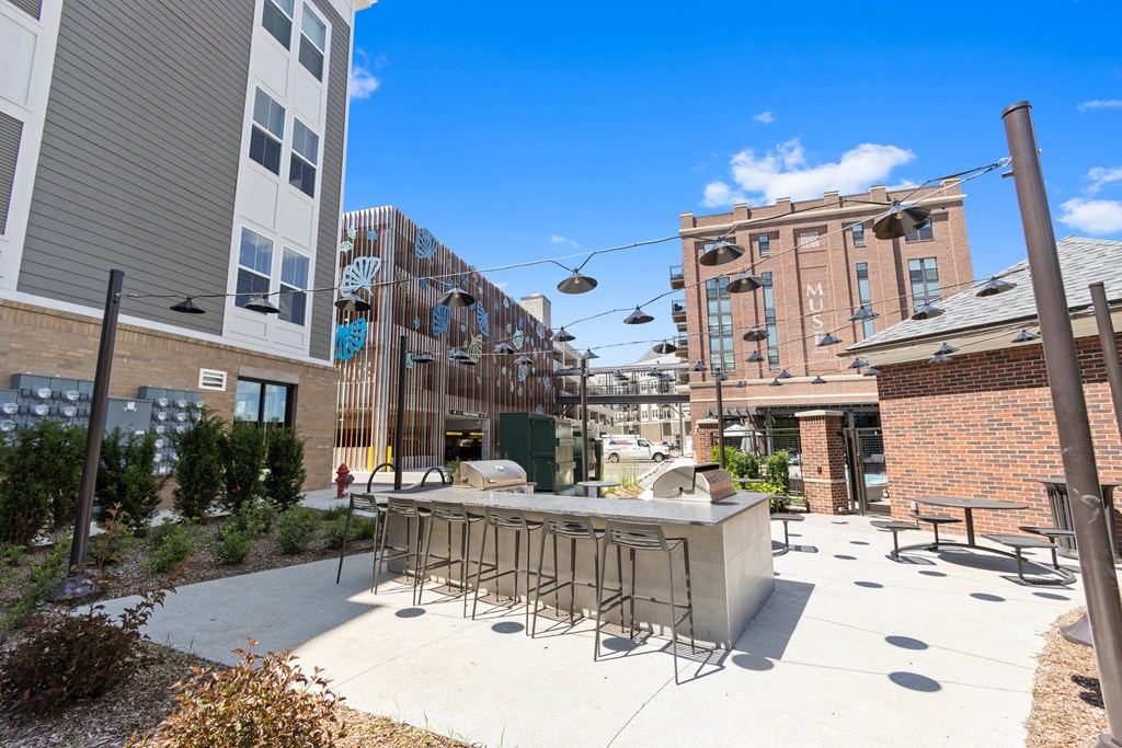 a patio with a bar and chairs in front of a building