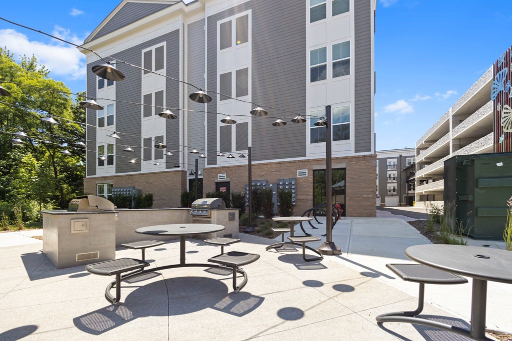 a patio with tables and chairs in front of an apartment building