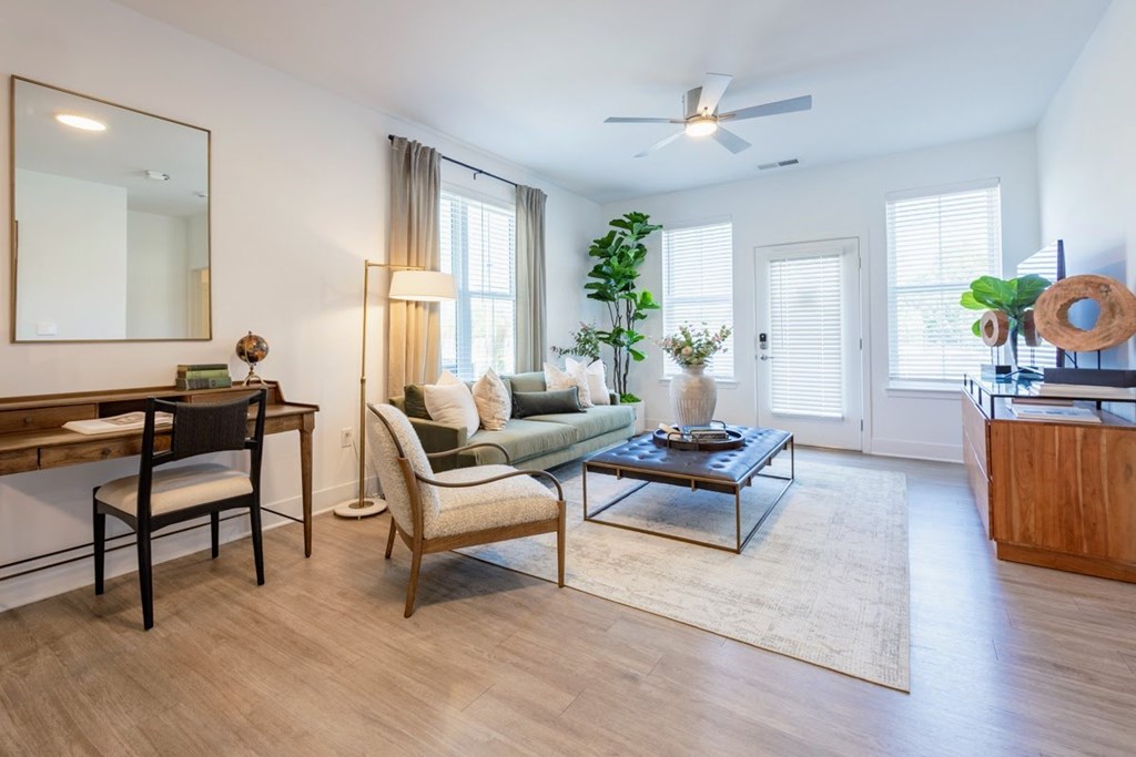 Apartment living room with work-from-home desk, natural lighting, and ceiling fan