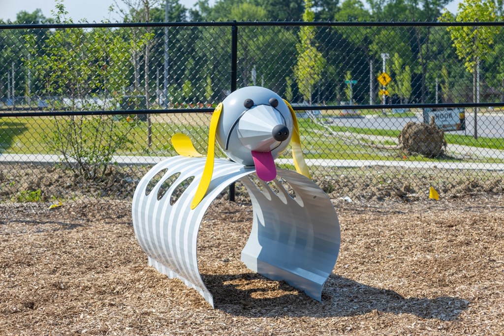 A metal sculpture of a dog with a yellow ribbon around its neck.