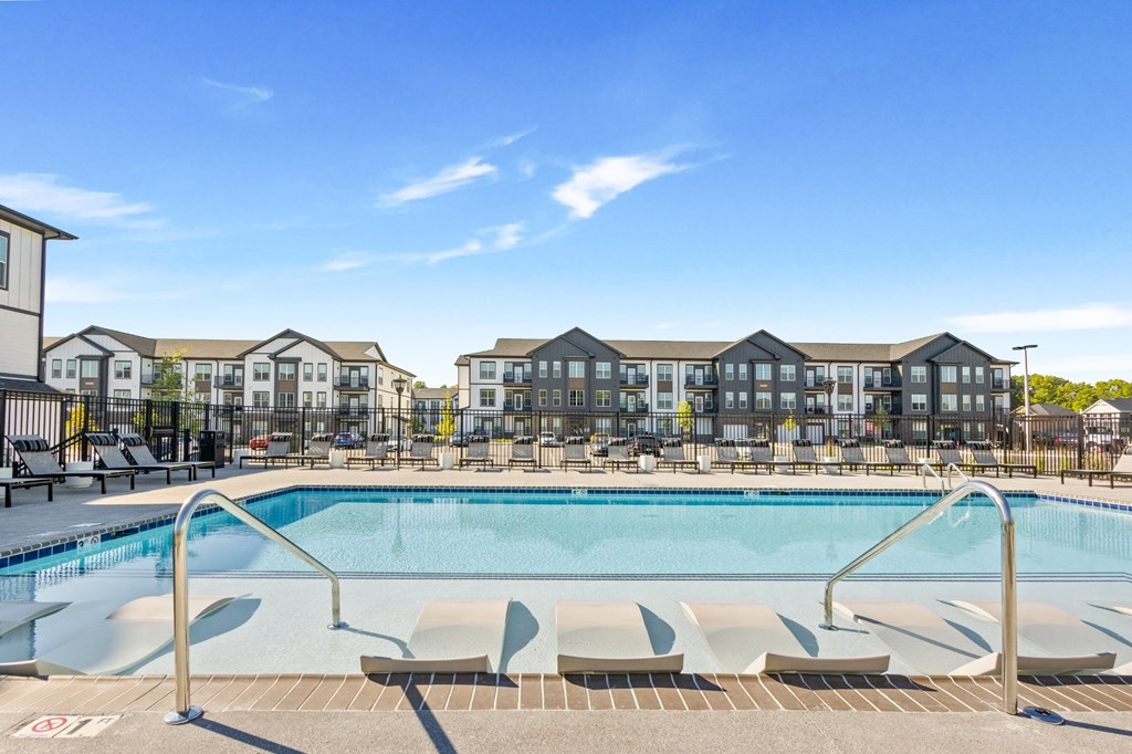 Apartment community pool with in-water loungers and surrounding buildings at Nook Nine