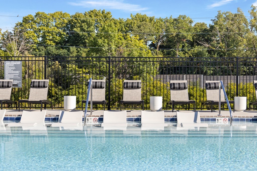 Poolside loungers with headrests and in-water tanning ledge at Nook Nine apartments