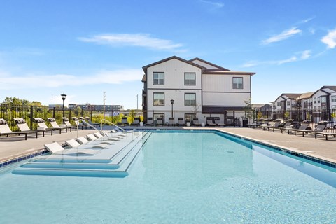 A pristine pool area with built-in in-water loungers, surrounded by black fencing and contemporary pool furniture—highlighting the upscale outdoor amenities at Montage West Lafayette Apartments, West 