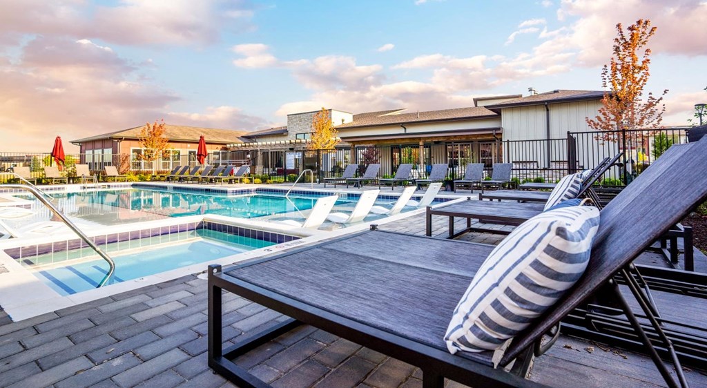 a swimming pool with chairs and tables next to a resort style pool