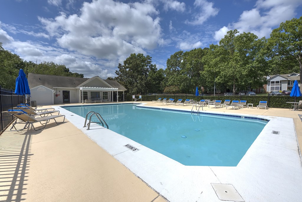 A large outdoor swimming pool with sun loungers and a pavilion in the background.