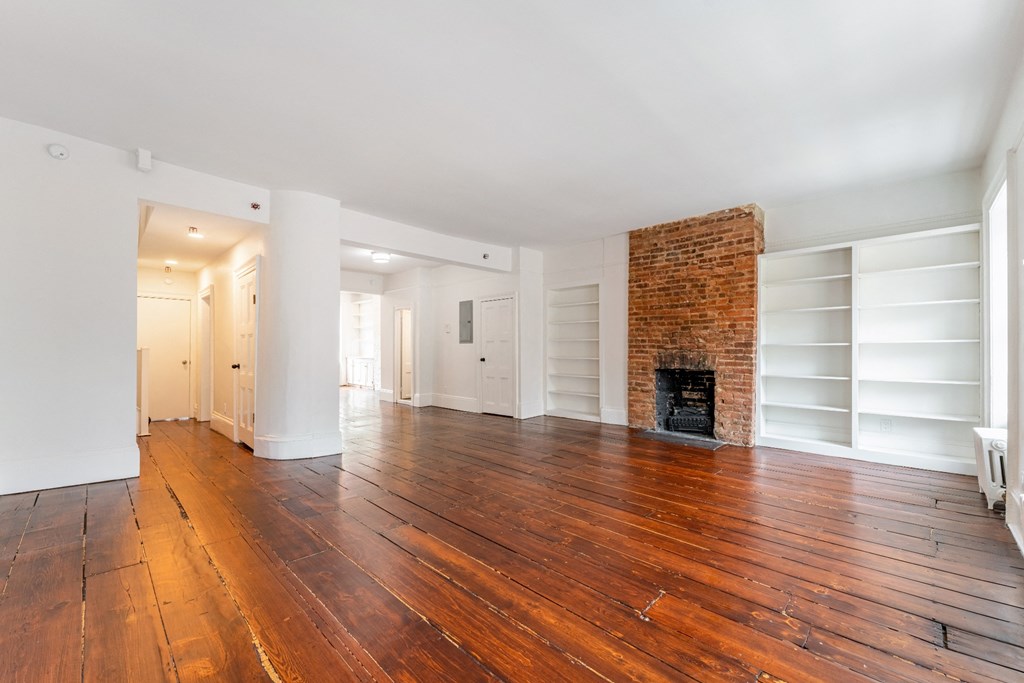 a living room with hardwood floors and a brick fireplace