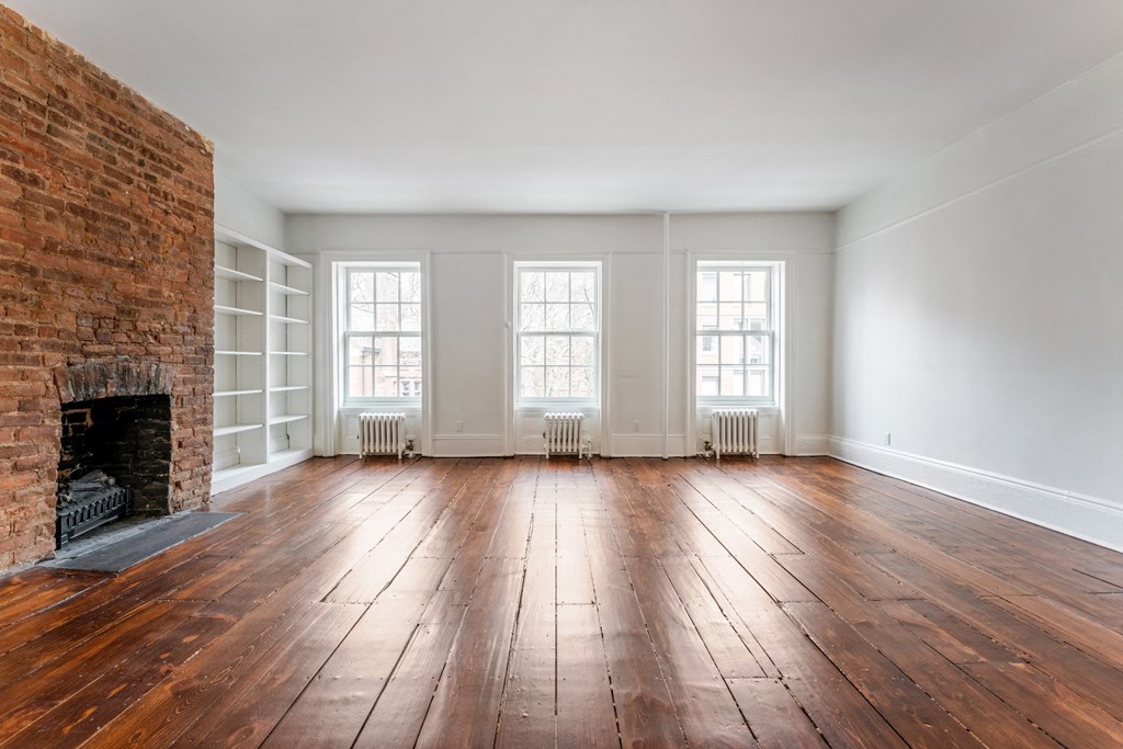 an empty living room with a brick fireplace and white walls
