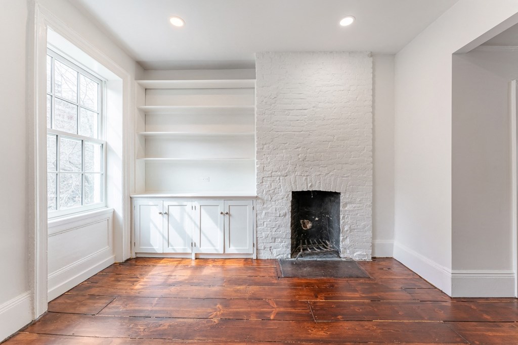 a living room with a brick fireplace and white walls