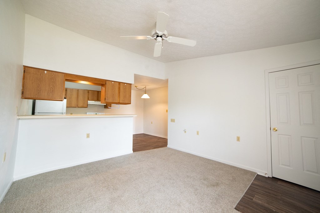 a bedroom with a ceiling fan and a kitchen in the background