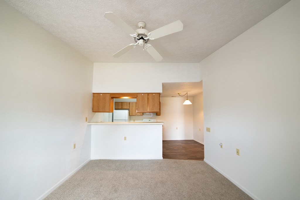 a bedroom with a ceiling fan and a kitchen in the background