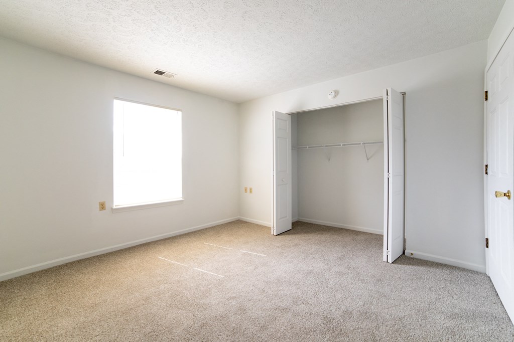 an empty bedroom with a closet and a window