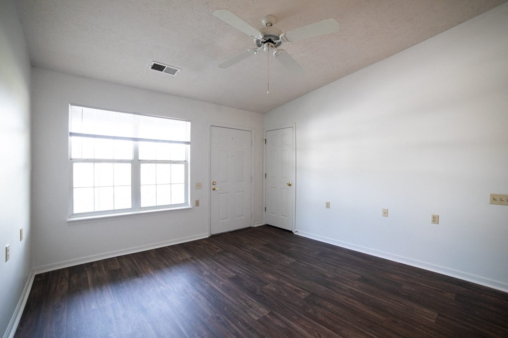 a bedroom with white walls and hardwood floors