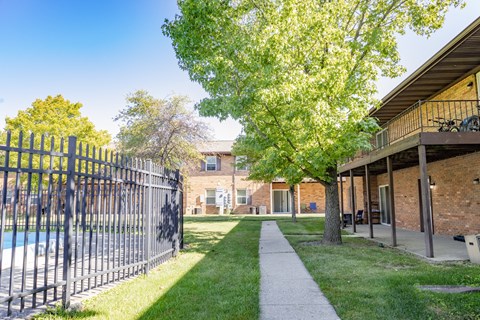 A black metal fence borders a pool in a sunny backyard.