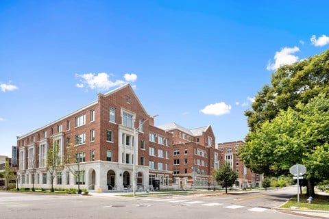 A large red brick building with white trim and a white fence in front.