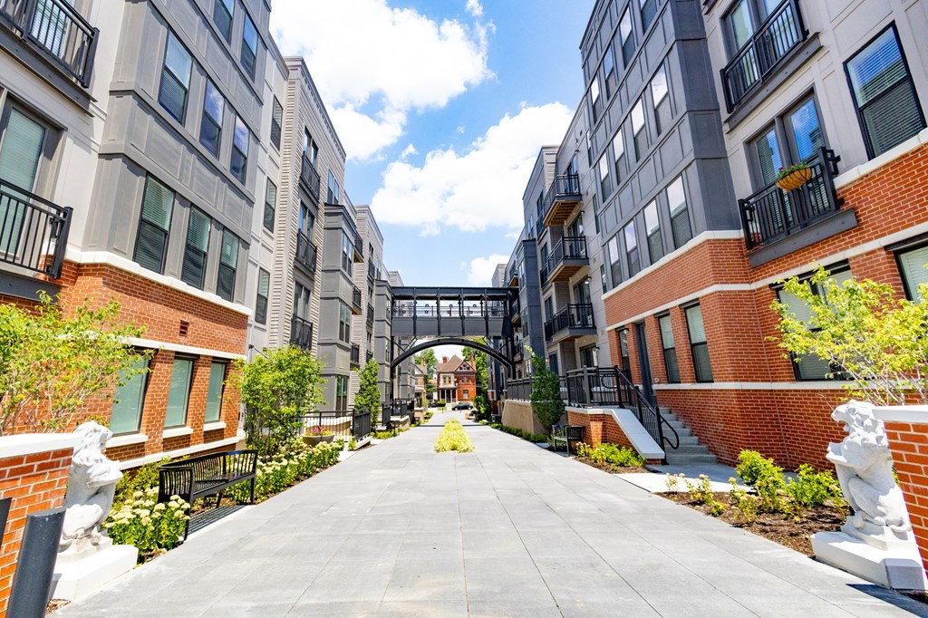 a courtyard between two apartment buildings with a bridge