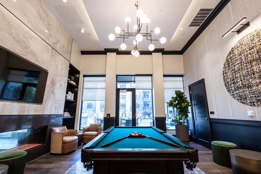 a pool table sits in the middle of a room with a large chandelier above it