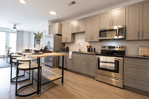 a large kitchen with stainless steel appliances and a table with chairs