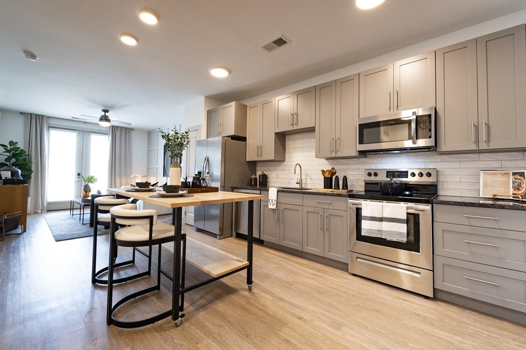 a large kitchen with stainless steel appliances and a wooden table with four chairs