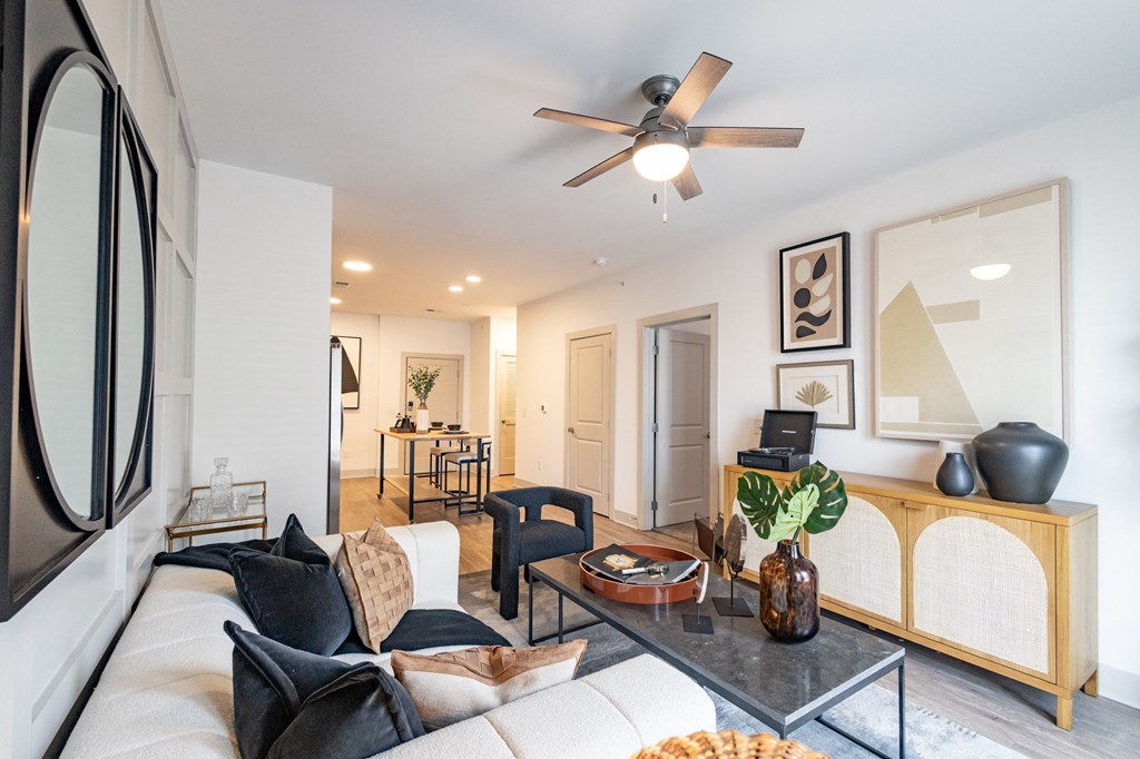 a living room with white walls and a ceiling fan