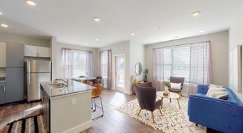 A modern kitchen with a blue couch in the living room. at Echo Park at Perry Crossing Apartments, Plainfield