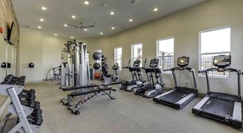 A spacious gym with a variety of equipment including treadmills, elliptical machines, and weight machines at Echo Park at Perry Crossing Apartments, Plainfield, Indiana