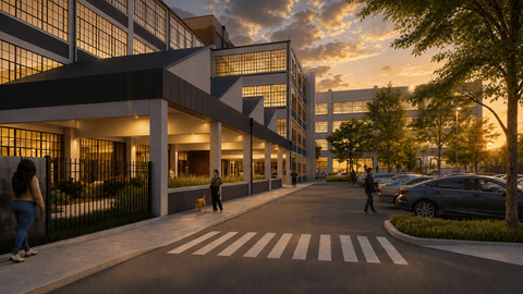 A modern building with a black fence and people walking on the sidewalk.