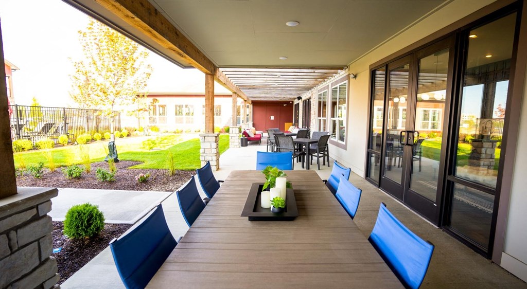 a patio with blue chairs and a table