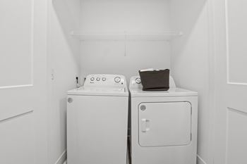 In-unit laundry at Nook Nine with washer, dryer, and overhead storage shelf.