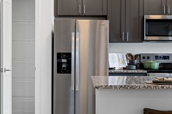 Kitchen at Nook Nine with stainless steel refrigerator, granite countertops, and spacious pantry.