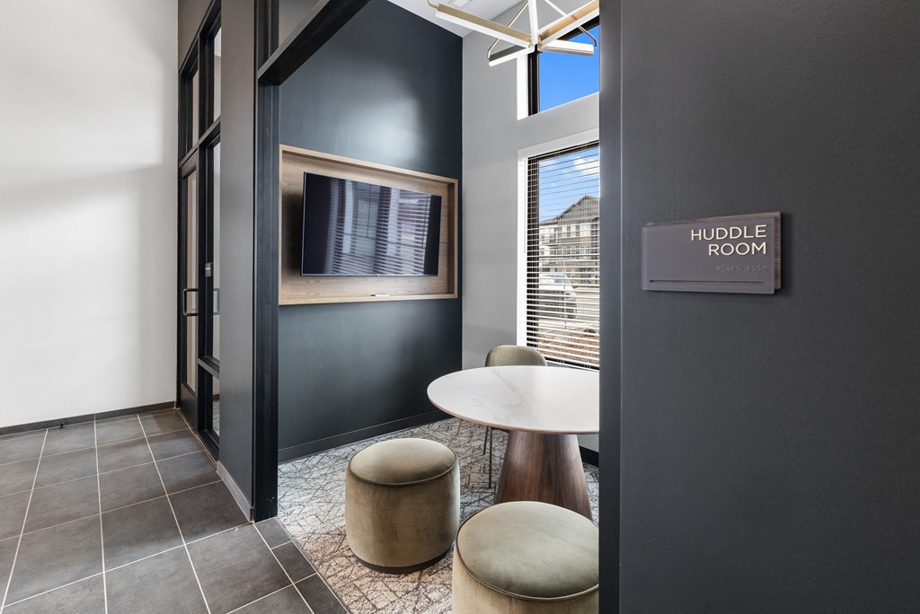 Modern huddle room at Nook Nine with a TV, cozy seating, and natural light for collaboration.