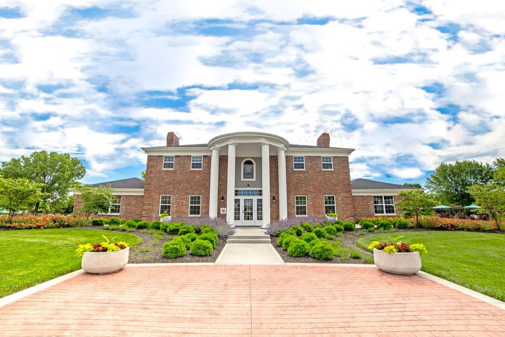 the front of a brick house with a walkway and gardens