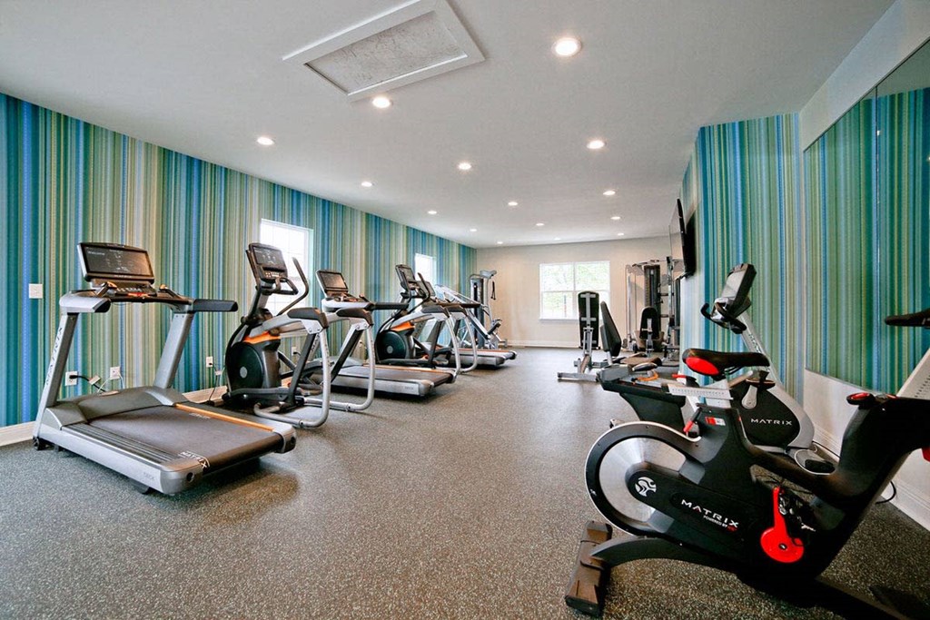 a gym with cardio equipment and weights on the floor