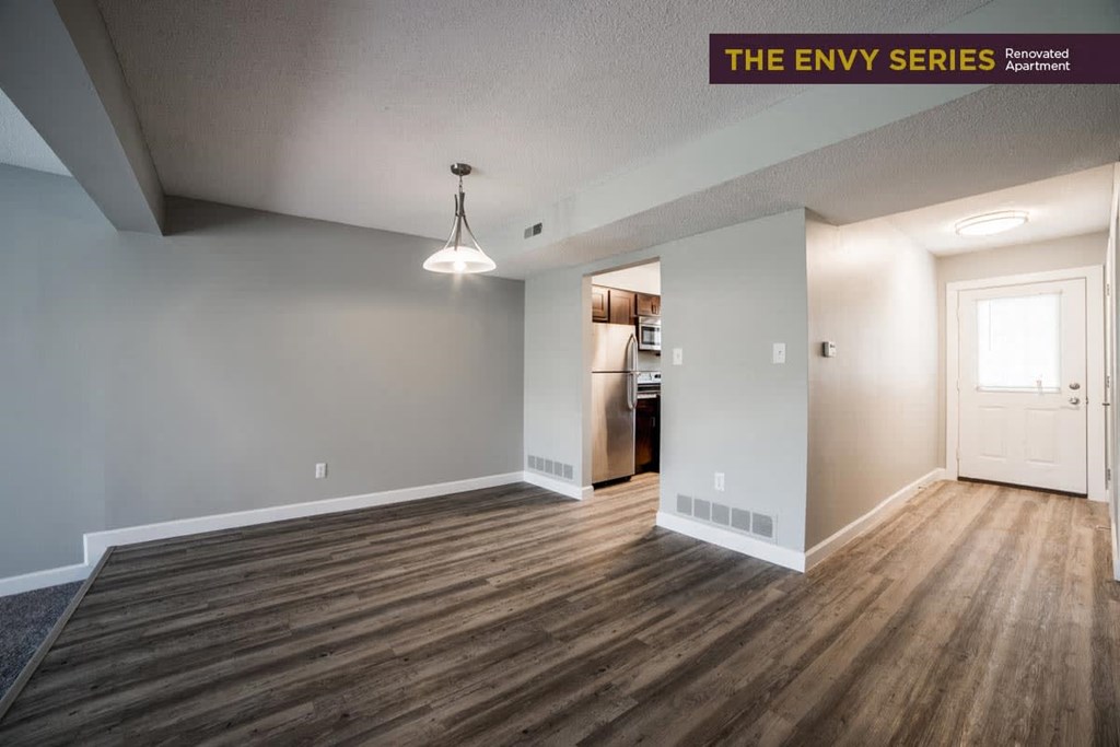 an empty living room with wood flooring and white walls