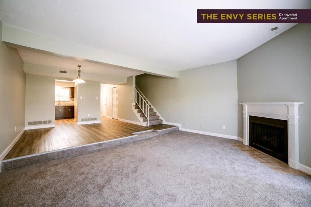an empty living room and dining room with a fireplace