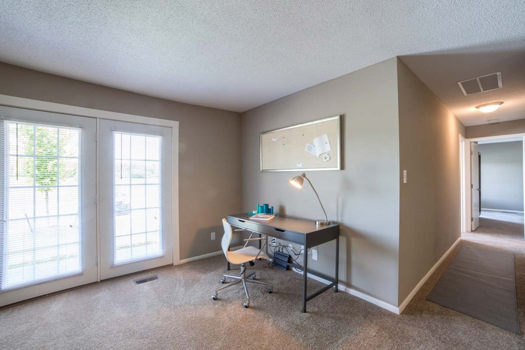 a home office with a desk and a door to a patio