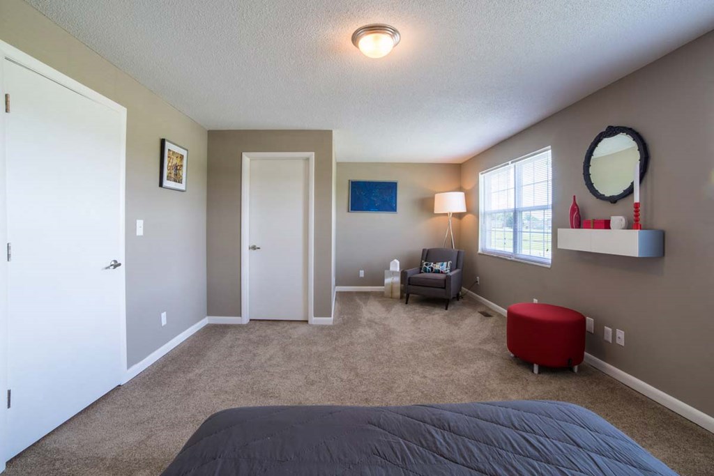 a bedroom with a bed and a chair and a window